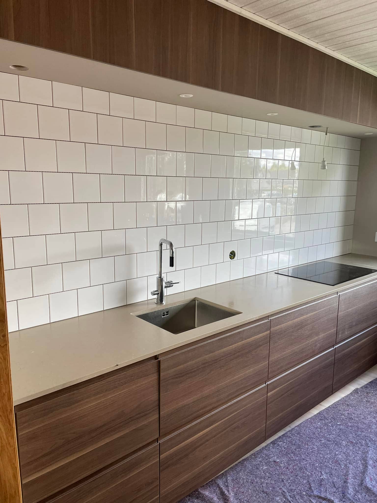 Modernt kök med stenskiva och vita kakelplattor.