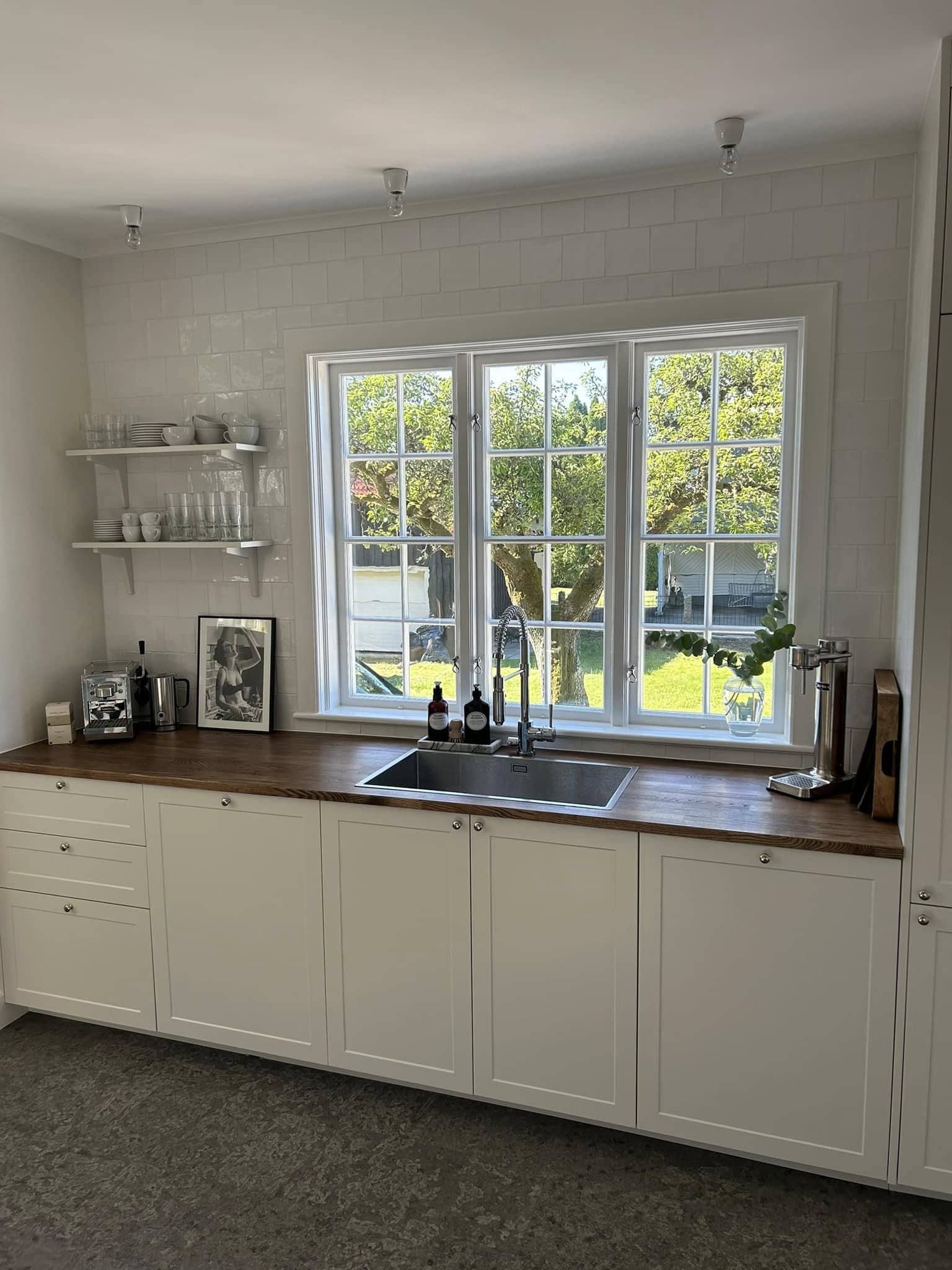 Lantligt kök med 3 höga fönster bakom diskbänken.