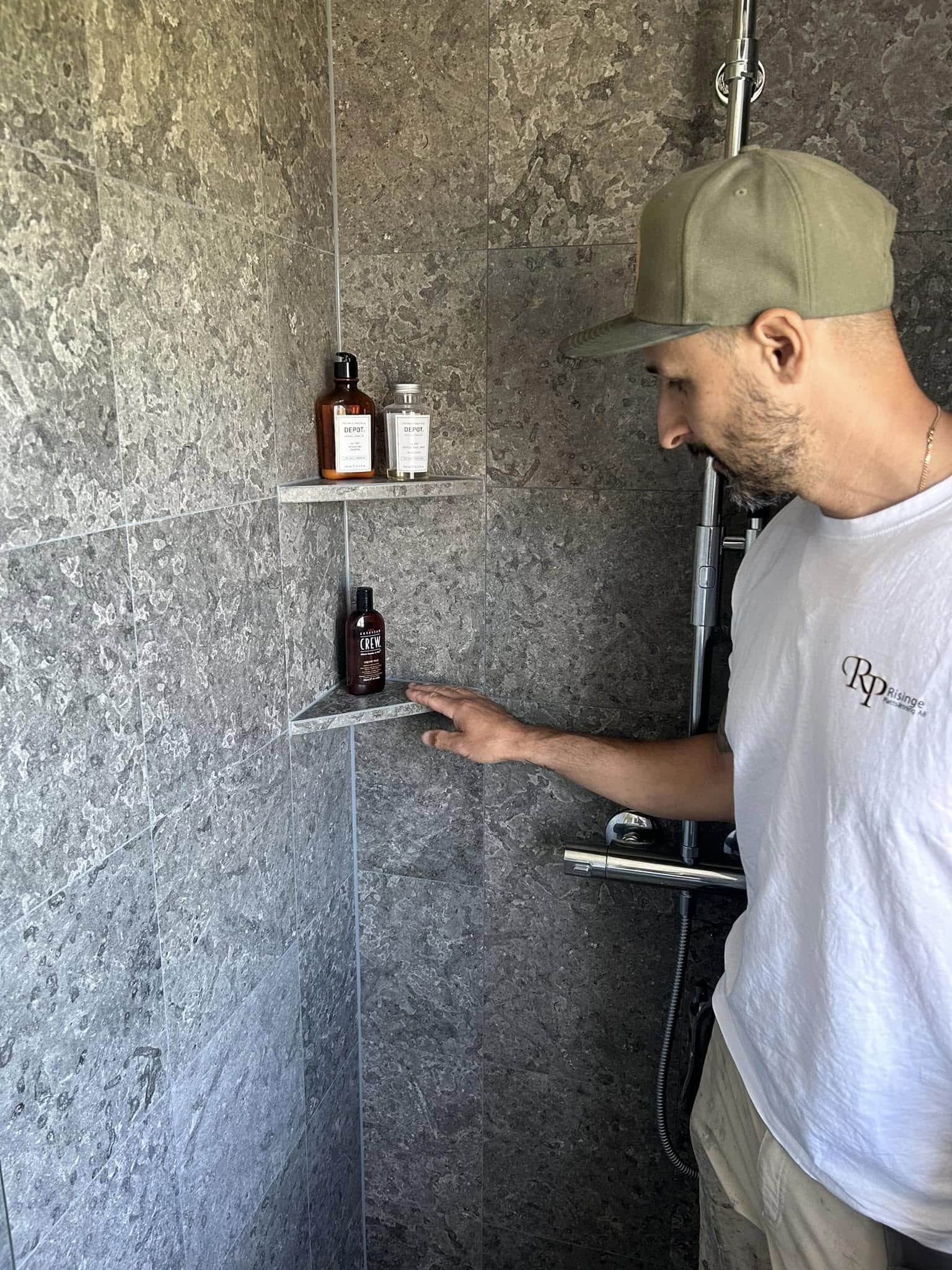 Plattsättare som visar platsbyggda hyllor i duschutrymmet i ett modernt badrum.